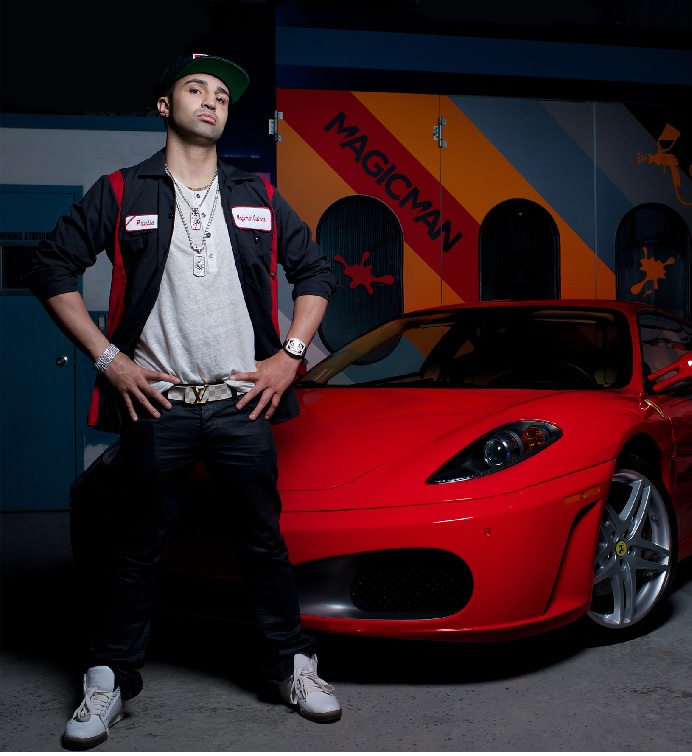 Paulie Malignaggi standing in front of his red Ferrari F430 while wearing a grey shirt, black jacket and black pant